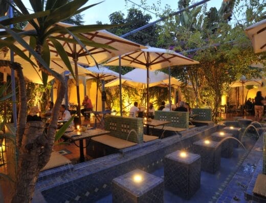 La Sqala est un charmant restaurant situé dans un jardin luxuriant, doté de tables élégantes et de parasols colorés.