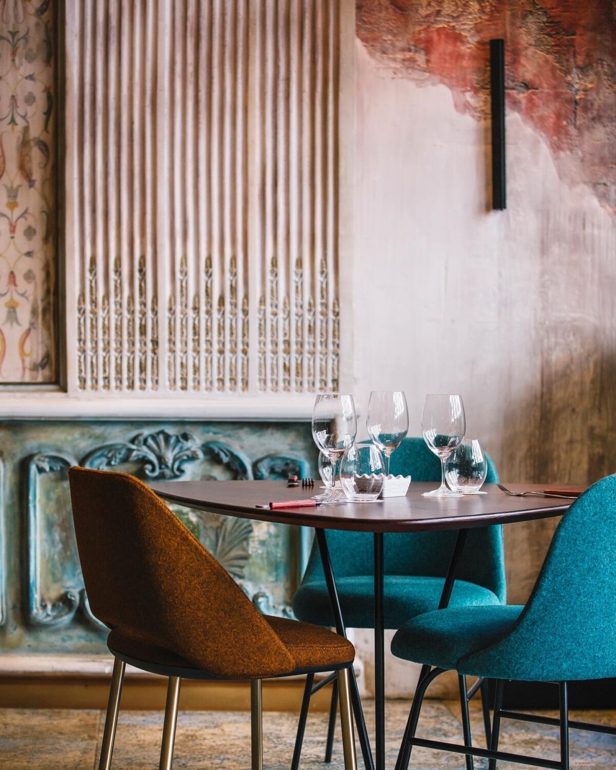 Une salle à manger da nolita avec une table et des chaises devant un mur orné.