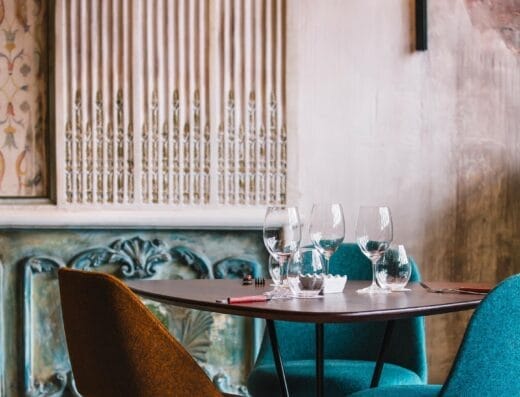 Une salle à manger da nolita avec une table et des chaises devant un mur orné.